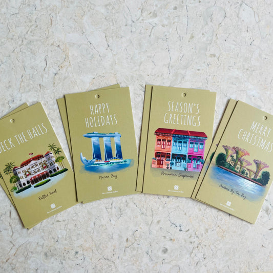 A set of eight Christmas-themed gift tags with various designs of Singapore landmarks, laid out on a surface.