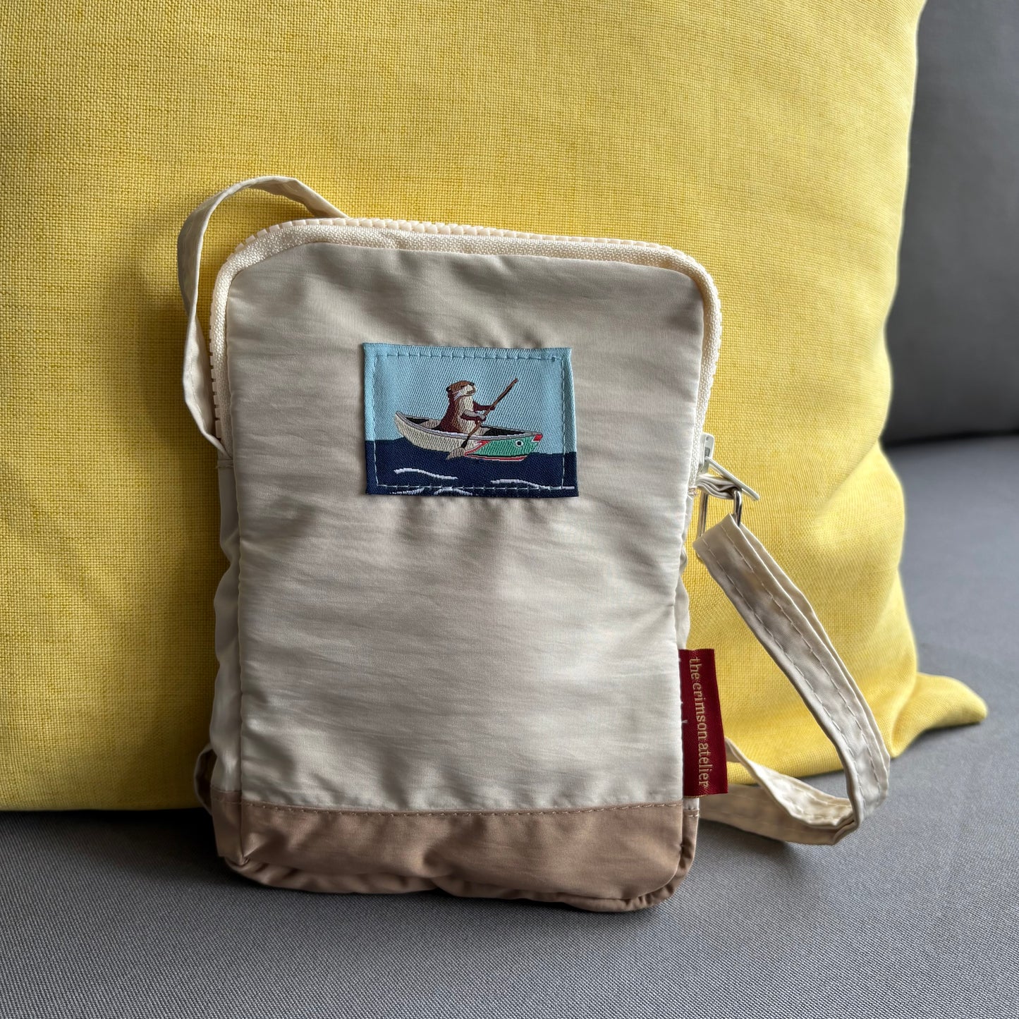 Otterwise Crossbody Bag front with woven logo of otter on the riverboat
