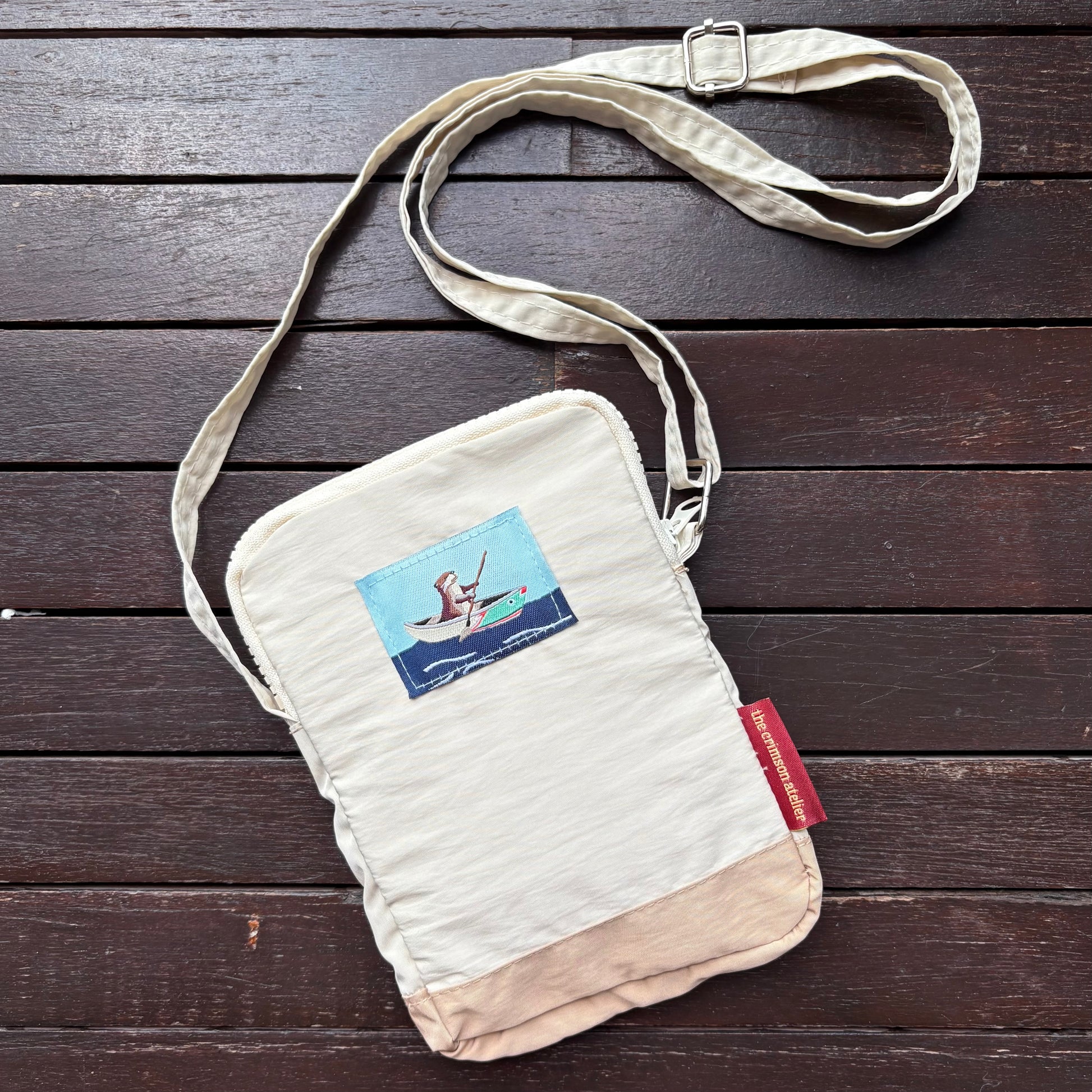Otterwise Crossbody Bag front with woven logo of otter on the riverboat