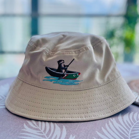 A reversible bucket hat for kids with embroidery of an otter paddling on the front