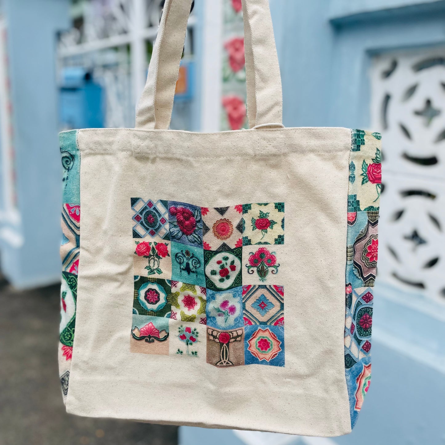 A beige cotton tote bag with a multicolored floral motifs showcasing a Peranakan tiles
