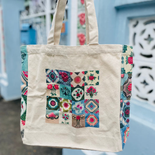 A beige cotton tote bag with a multicolored floral motifs showcasing a Peranakan tiles