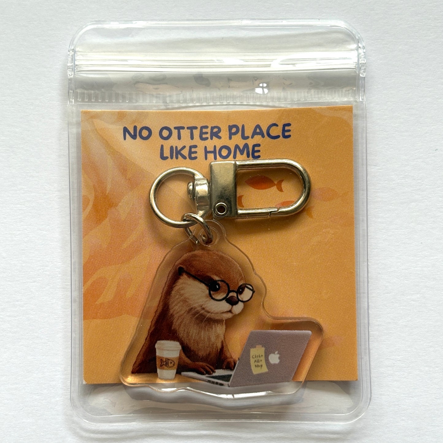 Keychain with an otter working on a laptop