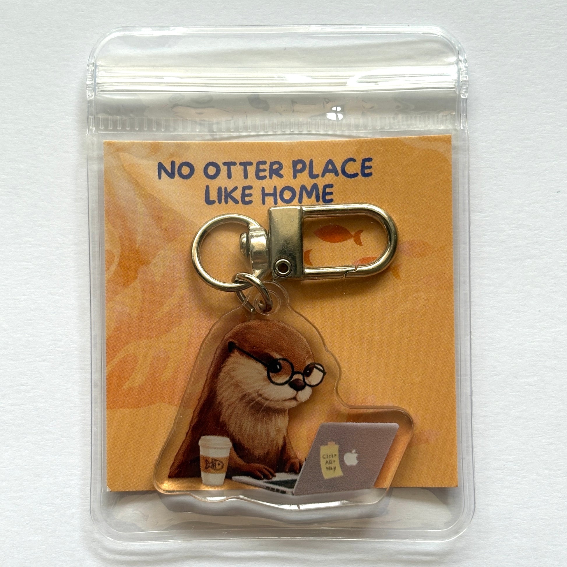 Keychain with an otter working on a laptop