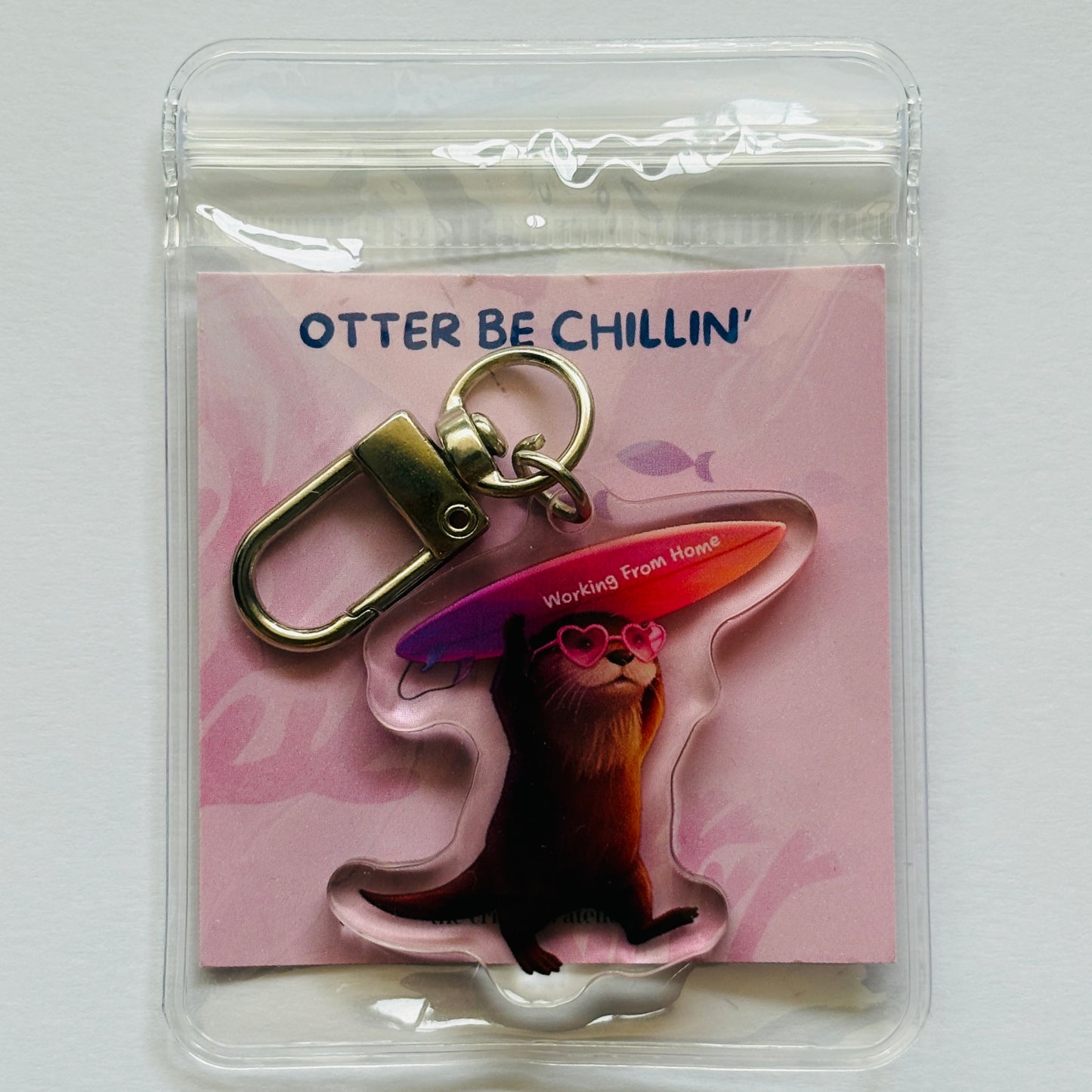 Keychain with otter and surfboard design on a pink card labeled 'Otter Be Chillin''.